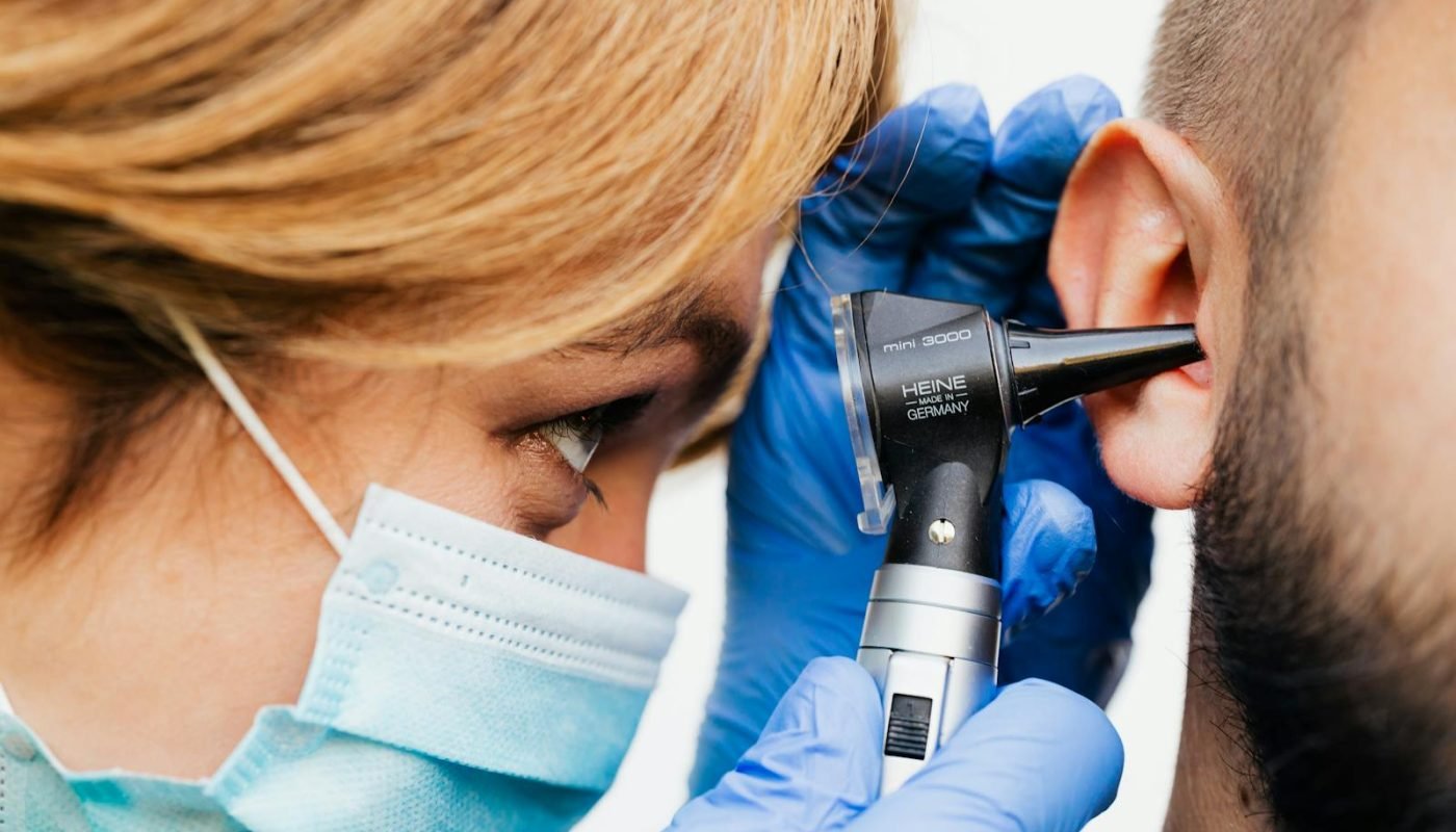 Gros plan d'un médecin effectuant un examen de l'oreille avec un otoscope.