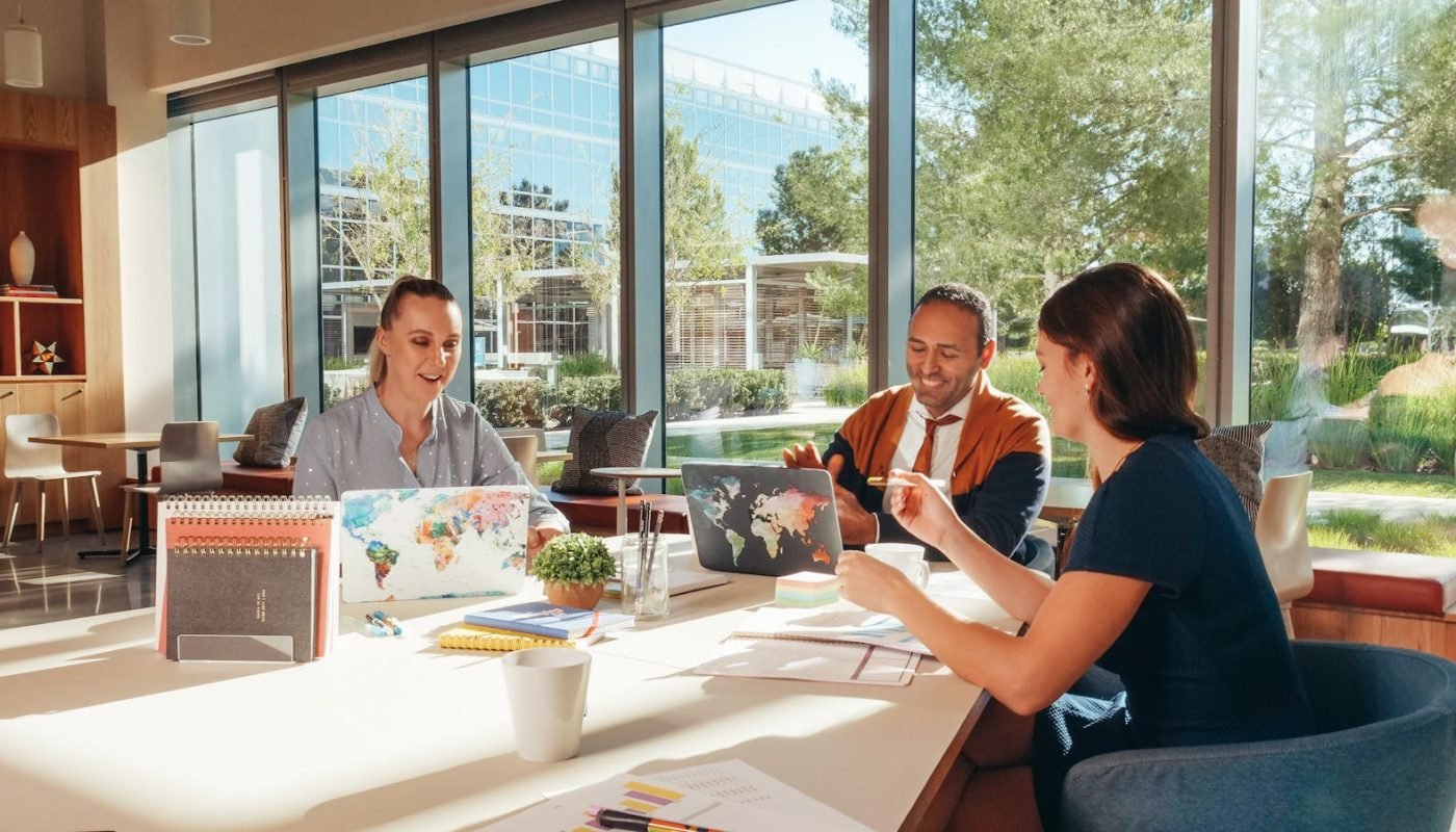 Trois collègues réfléchissent avec des ordinateurs portables dans un bureau bien éclairé.