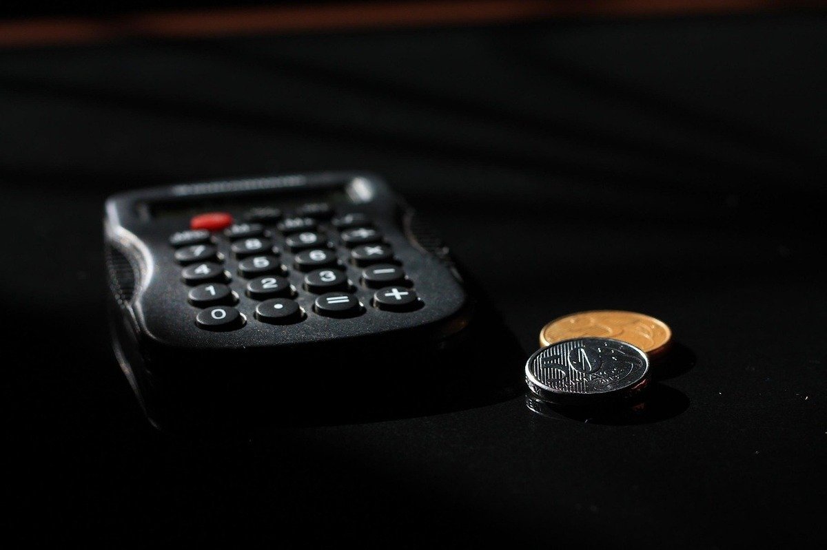 Calculatrice noire avec pièces de monnaie sur une surface sombre Calculatrice noire avec pièces de monnaie sur une surface sombre