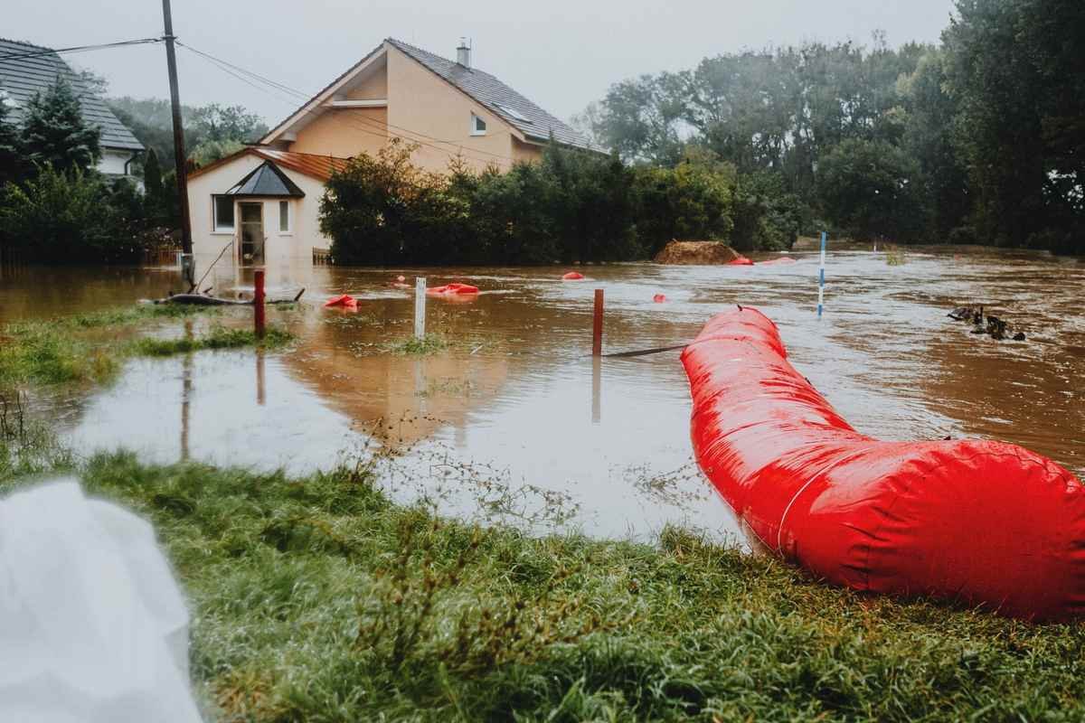 Rue inondée devant une maison, tube rouge et herbe mouillée