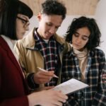 Trois individus consultent attentivement un papier, une note prise, dans un espace domestique