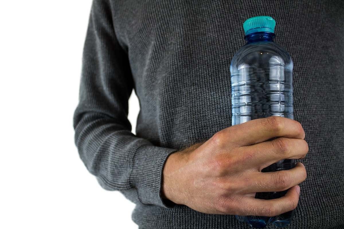 Un homme serre une bouteille d'eau plastique verte