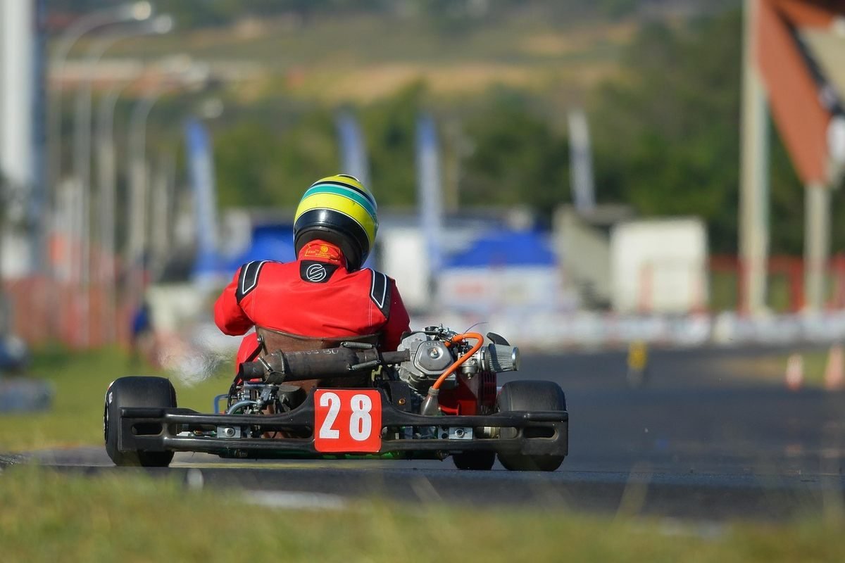Un coureur en combinaison rouge et casque pilote un kart Un coureur en combinaison rouge et casque pilote un kart