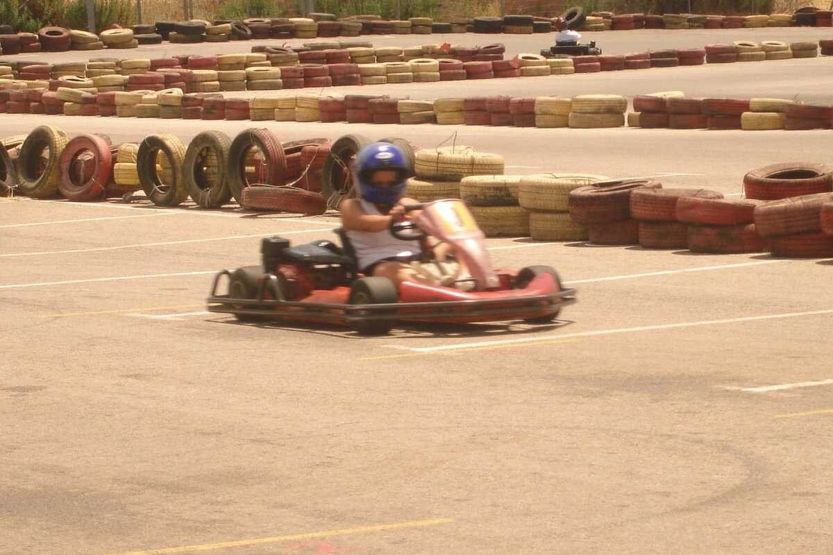Un pilote en kart rouge conduit sur une piste de karting