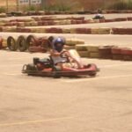 Un pilote en kart rouge conduit sur une piste de karting